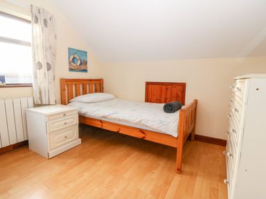 A bedroom with a single wooden bed a nightstand and a chest of drawers at Rhiangwyn Cottage Llanrhyddlad near Cemaes Bay
