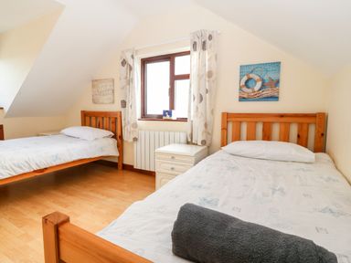 A bedroom with two single wooden beds and a window in between at Rhiangwyn Cottage in Llanrhyddlad near Cemaes Bay