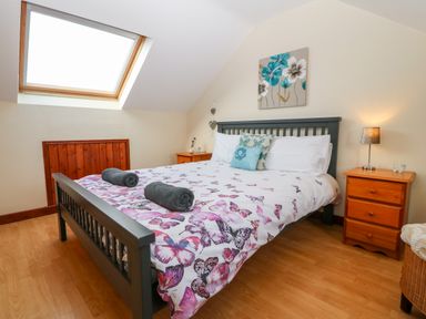 A bedroom with a bed covered in butterfly patterned bedding and two bedside tables with lamps at Rhiangwyn Cottage in Llanrhyddlad near Cemaes Bay