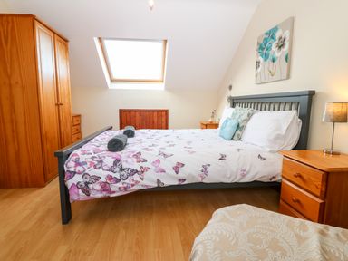 A bedroom with a double bed, wooden wardrobes, bedside tables, and a skylight window at Rhiangwyn Cottage Llanrhyddlad near Cemaes Bay