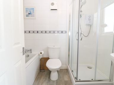 A bathroom with a bathtub toilet and glass shower enclosure at Rhiangwyn Cottage Llanrhyddlad near Cemaes Bay