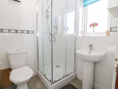 A bathroom with a toilet shower cubicle and pedestal sink at Rhiangwyn Cottage Llanrhyddlad near Cemaes Bay