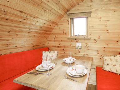 A dining area with a wooden table red bench seats and a window at Oak View in Llandovery