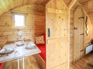 A wooden dining nook with a table set for two and a red cushioned bench at Oak View in Llandovery