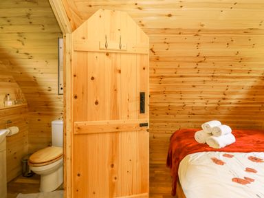 A bedroom with a bed and folded towels next to a bathroom with a toilet at Oak View in Llandovery