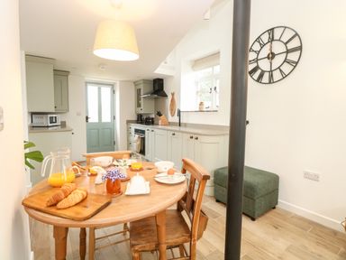 A kitchen with wooden table and chairs set for breakfast and green cabinets at Wensum Spring in Horningtoft near Fakenham