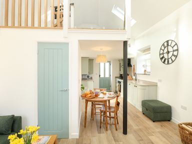 A kitchen and dining area with a wooden table set for breakfast and green doors at Wensum Spring in Horningtoft near Fakenham