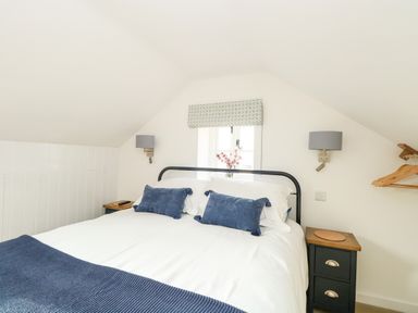 A bedroom with a double bed two blue pillows and two bedside tables at Wensum Spring in Horningtoft near Fakenham
