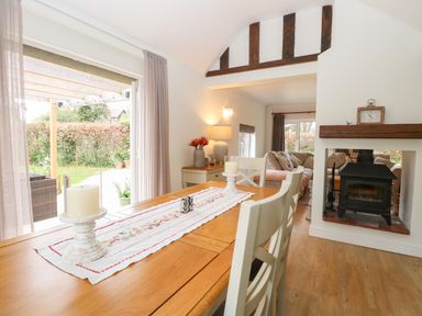 A dining table with candles and a table runner next to a fireplace and a living area at The Lodge in Wroxham