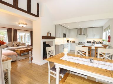 An open plan kitchen and dining area with wooden furniture and a living room with a sofa and a coffee table at The Lodge in Wroxham