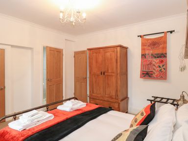 A bedroom with a bed with folded towels pillows a wooden wardrobe and a decorative wall hanging at The Lodge in Wroxham