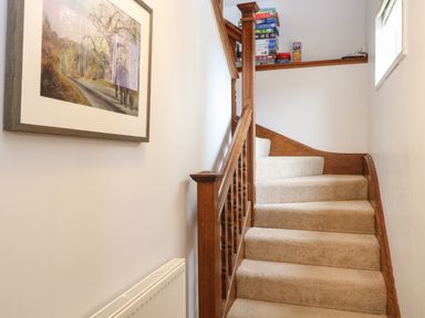 A carpeted staircase with wooden railing and board games on the landing at The Lodge in Wroxham