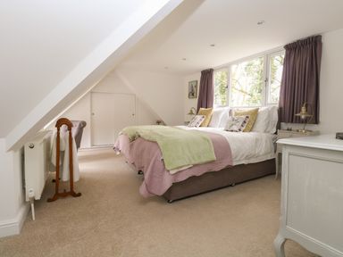 A bedroom with a double bed next to windows and bedside tables at The Lodge in Wroxham