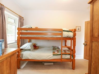 A bedroom with a wooden bunk bed with stuffed animals on each bed at The Lodge in Wroxham