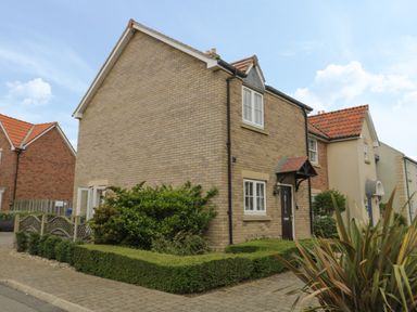 A brick house with a small garden and hedge in front at Driftwood in Filey