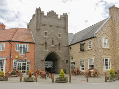 A courtyard with tables and chairs outside buildings with stone and brick walls at Driftwood in Filey