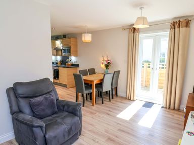 An open plan living and dining area with a dining table and chairs at Driftwood in Filey