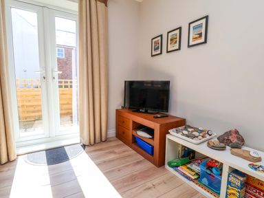 A living room with sliding doors and a television at Driftwood in Filey