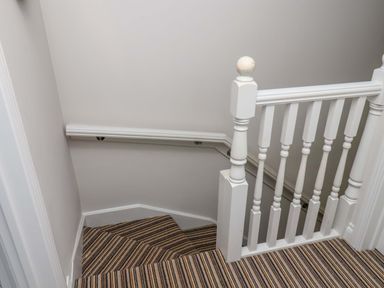 A staircase with carpet and handrail at Driftwood in Filey