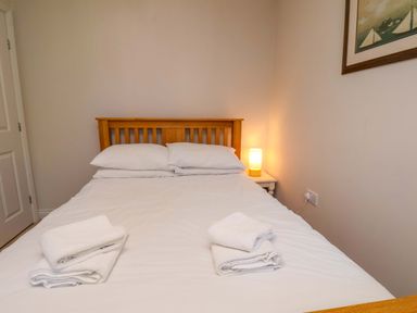 A bedroom with a wooden bed and towels at Driftwood in Filey