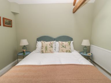 A bedroom with a double bed two bedside tables with lamps and framed pictures on the wall at Todridge Barn in Corbridge