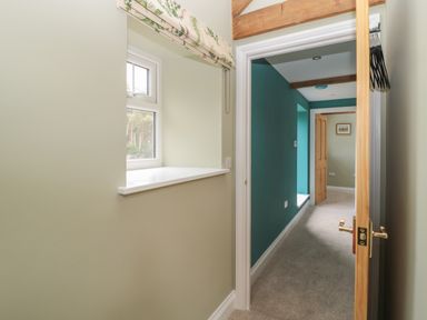 A hallway with a window sill and open wooden door leading to another room at Todridge Barn in Corbridge