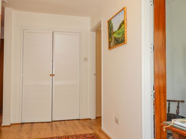A hallway with wooden floor a white double door a wall painting and part of a wooden framed glass door at Goldcrest in Newport Pembrokeshire