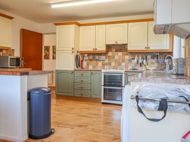A kitchen with cabinets stove microwave and trash bin at Goldcrest in Newport Pembrokeshire