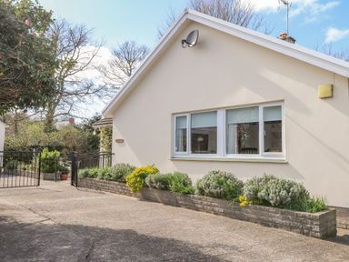 Exterior side view of a house with a window flower bed and gate at Goldcrest in Newport Pembrokeshire