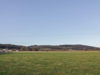 A grassy field with a wooden fence and hills in the background at The Croft in Leigh Sinton