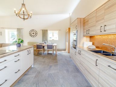 A kitchen with wooden cabinets a dining table with four chairs and a chandelier at The Croft in Leigh Sinton