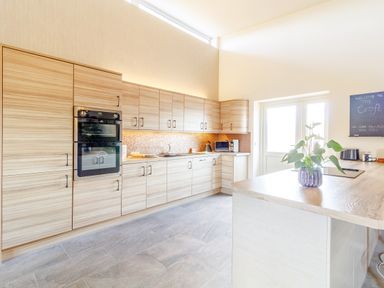 A kitchen with wooden cabinets an oven a plant on the countertop and a door at The Croft in Leigh Sinton