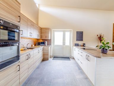 A kitchen with wooden cabinets white counters and a double door at The Croft in Leigh Sinton