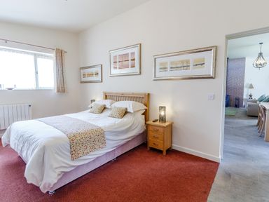 A bedroom with a double bed bedside table and three framed pictures on the wall at The Croft in Leigh Sinton