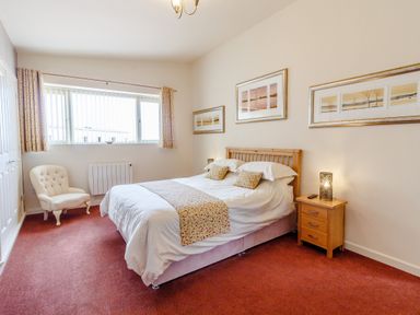A bedroom with a double bed bedside table armchair and three framed pictures on the wall at The Croft in Leigh Sinton