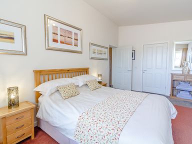 A bedroom with a double bed two bedside tables and framed pictures on the wall at The Croft in Leigh Sinton