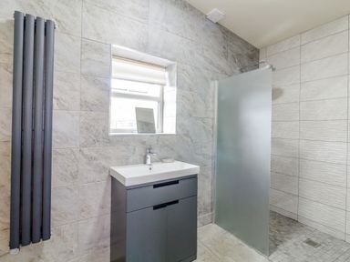 A bathroom with a sink cabinet a frosted glass shower screen and a window at The Croft in Leigh Sinton