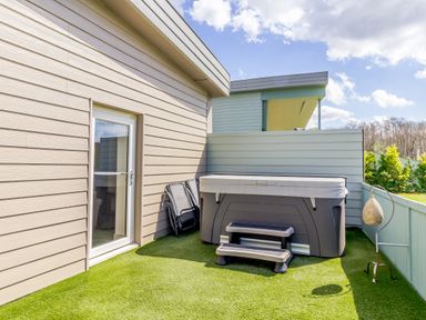 A balcony with a hot tub two folding chairs and a standing lamp at The Croft in Leigh Sinton