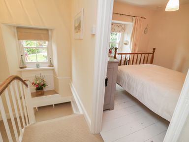 A stairway next to a bedroom with a wooden bed and a dresser at Fairfield Cottage in Boscastle
