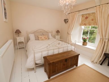 A bedroom with a white bed and wooden chest at Fairfield Cottage in Boscastle