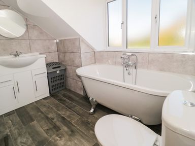 A bathroom with a clawfoot bathtub sink with cabinet mirror and toilet at Big Azzles in Tyn-y-Gongl near Benllech