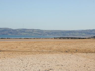 A beach view with sand and water at Big Azzles in Benllech