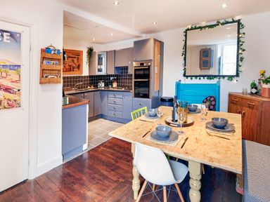 A kitchen and dining area with a wooden table set for four and grey cabinets at 1 Pringles Yard in Alnwick