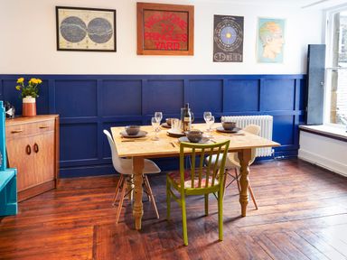 A dining area with a wooden table set for four and blue panelled walls at 1 Pringles Yard in Alnwick