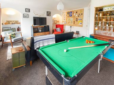 A living room with a pool table a sofa a red chair a television and shelves at 1 Pringles Yard in Alnwick