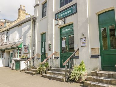 Exterior of a theatre building with green doors windows and stairs leading to the auditorium entrance in Chipping Norton