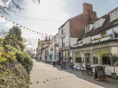 A street view with shopfronts and outdoor seating under bunting at Victoria Cottage in Chipping Norton