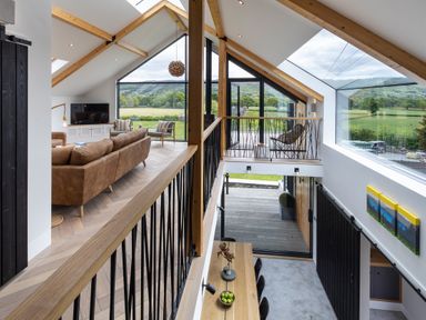 An upper living area with brown sofas and armchairs and a lower dining area with a wooden table and chairs at Gatesgarth in Coniston