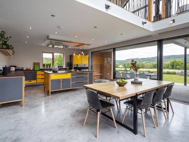 A modern kitchen and dining area with yellow and gray cabinets and a wooden dining table at Gatesgarth in Coniston