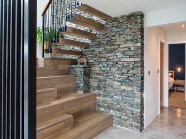 A wooden staircase with stone wall and a view into a bedroom at Gatesgarth in Coniston